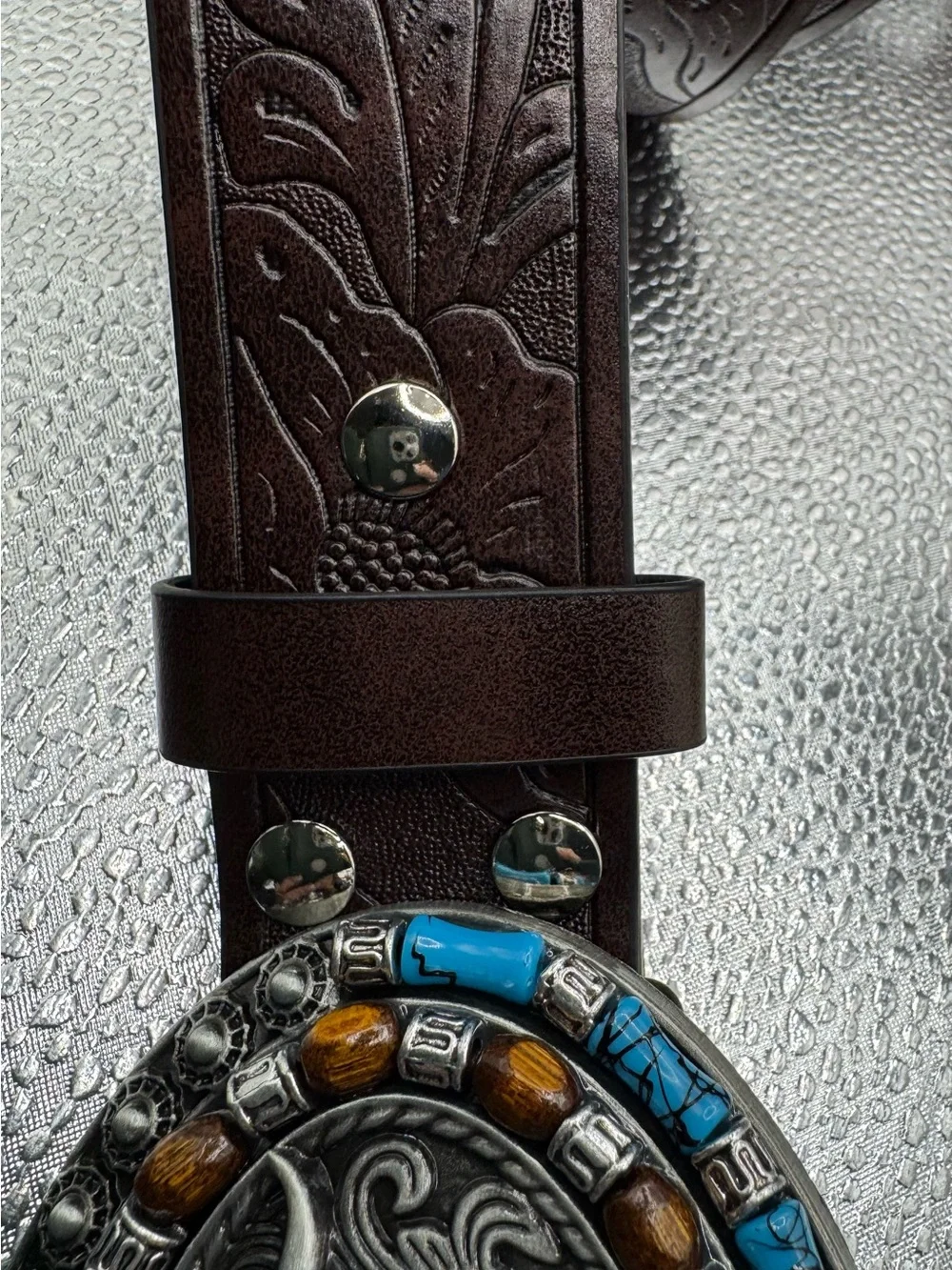 style longhorn skull belt buckle paired with a brown embossed leather strap.